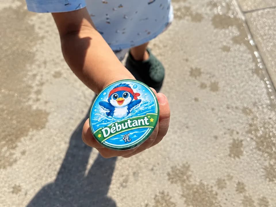 Un enfant montre son badge Débutant au bord de la piscine